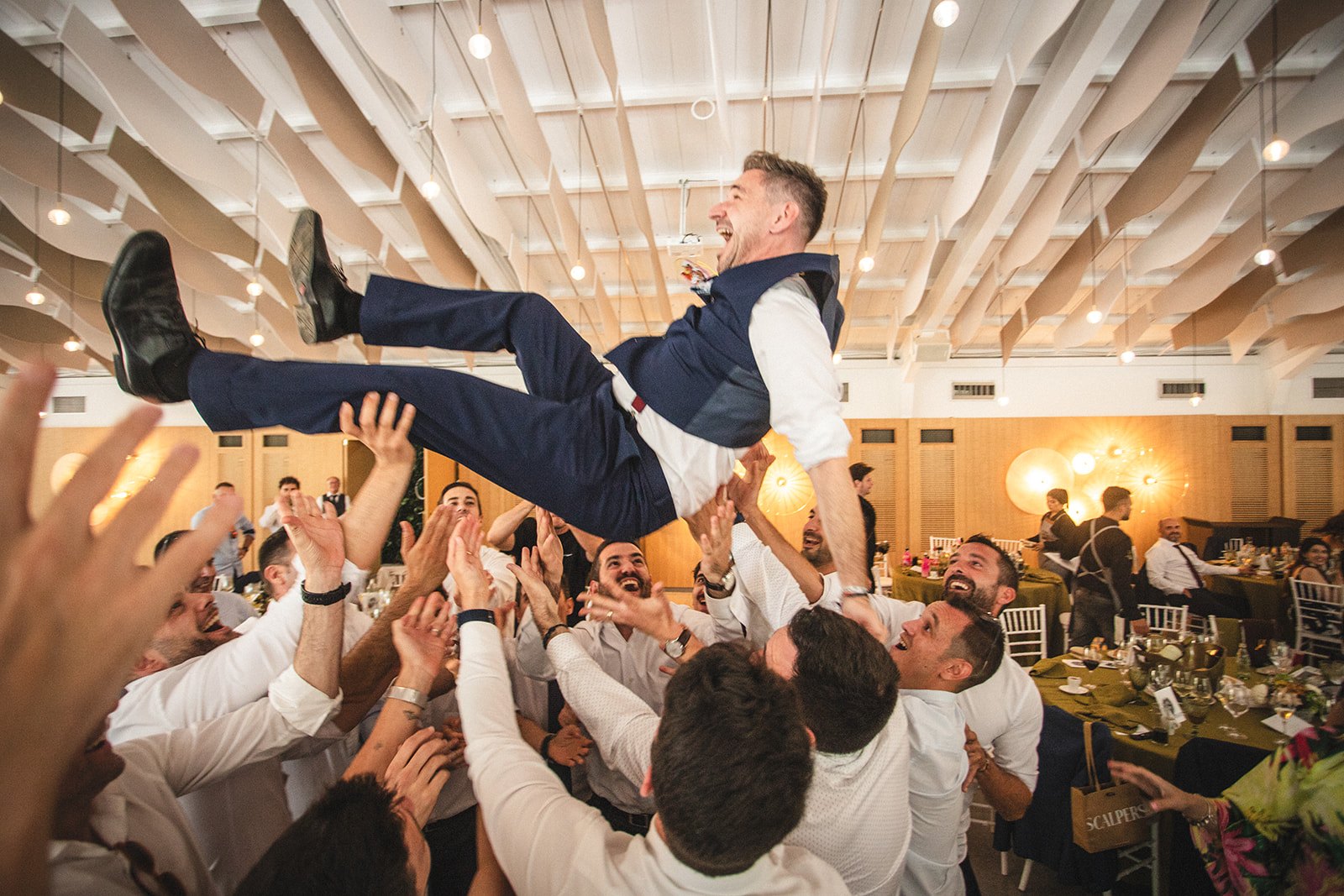 Celebración de boda, invitados levantando al novio